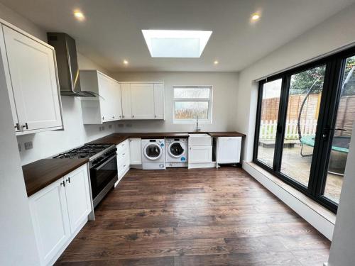 a kitchen with white cabinets and a washer and dryer at Lovely 4-Bed House in Central Wolverhampton in Wolverhampton