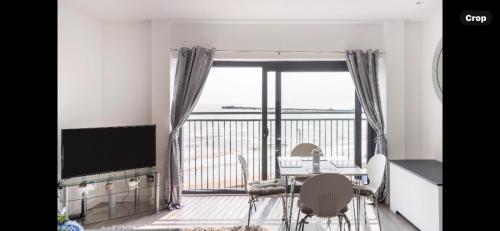 a dining room with a table and chairs and a large window at Penthouse Apartment with seaviews in Walton-on-the-Naze