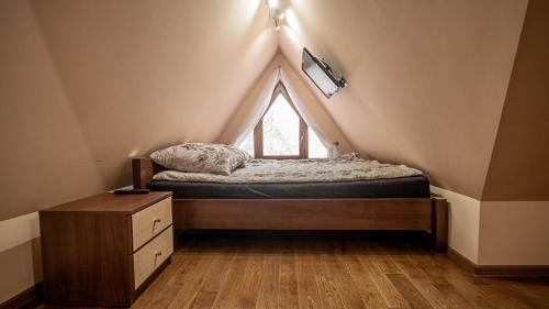sypialnia z łóżkiem i oknem na poddaszu w obiekcie Ainak Apartamenty w Zakopanem