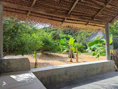 un banc sous un toit avec des arbres en arrière-plan dans l'établissement Dune Towers, à Alankuda