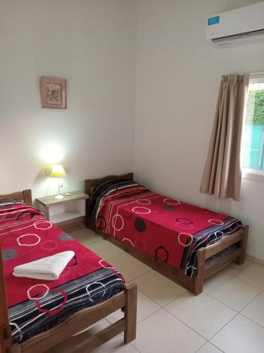 two beds in a room with a red blanket at Complejo La Palmera in San Rafael
