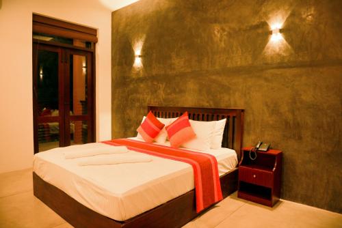 a bedroom with a bed with red and white pillows at Olanro Hotel Negombo in Negombo