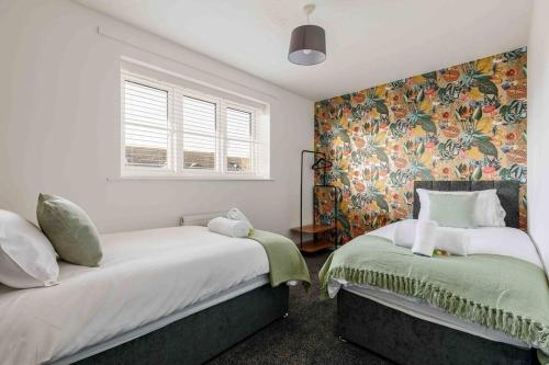 a bedroom with two beds and a floral wallpaper at 2 bedroom House-Driveway - Bournemouth Hospital - Long Stay Discounts - Lima Apartments Ltd in Bournemouth