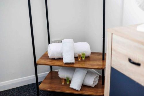 una pila de toallas en un estante del baño en 2 bedroom House-Driveway - Bournemouth Hospital - Long Stay Discounts - Lima Apartments Ltd en Bournemouth