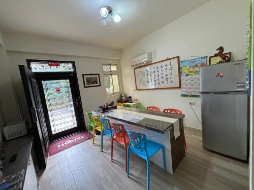 uma cozinha com frigorífico e bancos coloridos em 八八古藝悅禾民宿 em Jinning