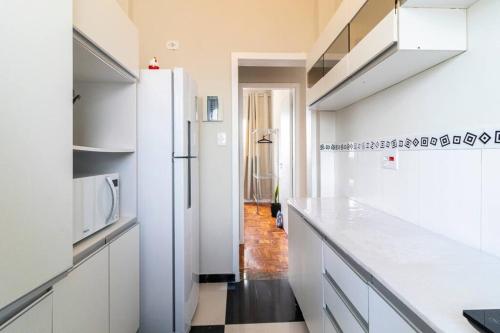 La cuisine est équipée de placards blancs et d'un réfrigérateur blanc. dans l'établissement Apartamento no coração de Pinheiros, à São Paulo