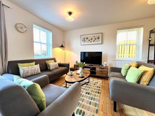 a living room with two couches and a tv at Cosy Cotswold Cottage - Jacobs Cottage in Cirencester