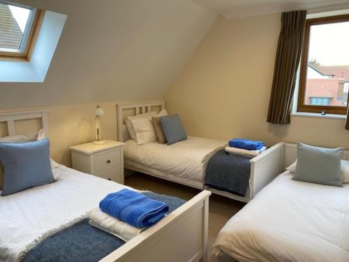 1 dormitorio con 2 camas y almohadas azules en Stylish contemporary seaside holiday home with 5 bedrooms, sea view, parking and EV point en Kent