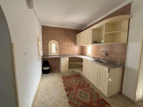 cocina con armarios blancos y alfombra roja en Prime location family beach villa - 16 pax en Alexandría
