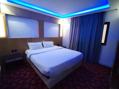 a bedroom with a large white bed with blue lights at ميرا سويت للشقق المخدومة in Jeddah