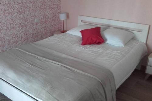 a white bed with a red pillow on it at Maison rénovée atypique, jardin, terrasse, Odet in Quimper