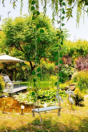 a swing in a garden with a pond with lilies at House Garden Loft in Baricella