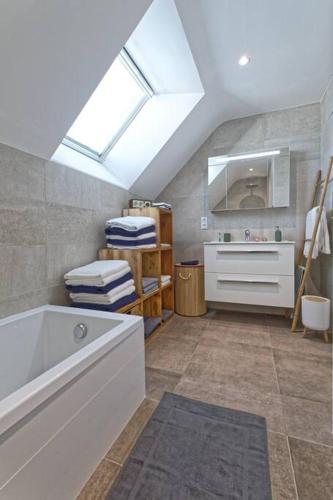 La salle de bains est pourvue d'une baignoire, d'un lavabo et d'une lucarne. dans l'établissement La terrasse du Porjou classée 3 étoiles, à Ploubazlanec