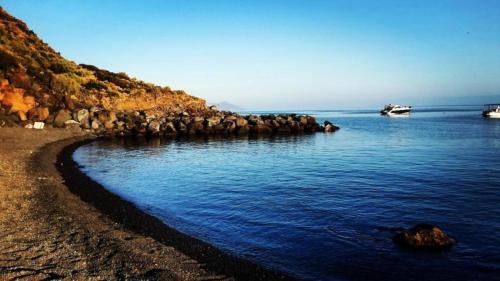 a rocky shore with a boat in the water at Casa del Geco in Rinella