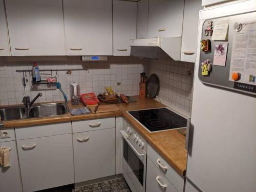 cocina con armarios blancos y nevera blanca en Praktisches Gästezimmer für eine Person, en Bergisch Gladbach