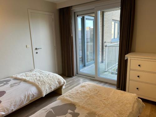 een slaapkamer met een bed en een glazen schuifdeur bij App Zouavenplein 0403 in Koksijde