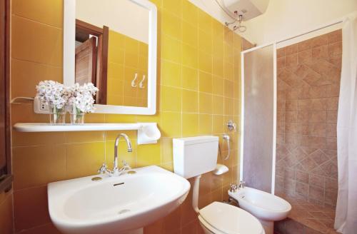 a bathroom with a sink and a toilet and a mirror at Pinus Village Appartamento in Santa Margherita di Pula