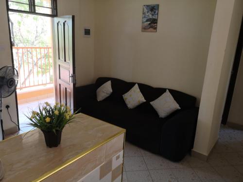 Diani Ocean View Apartment في أوكوندا: أريكة سوداء مع وسائد في غرفة المعيشة