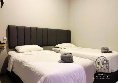 2 Betten mit Hüten darüber in einem Zimmer in der Unterkunft Jesselton Quay CityView @NeoStay in Kota Kinabalu