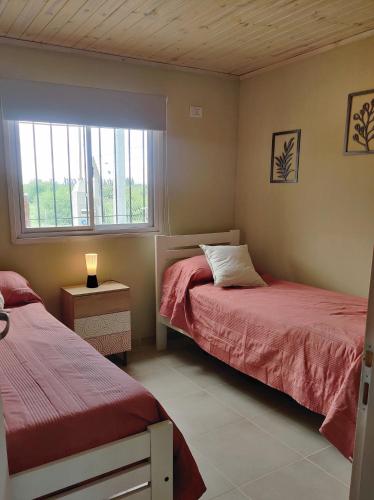 a bedroom with two beds and a window at Casa Okukuy in Cafayate