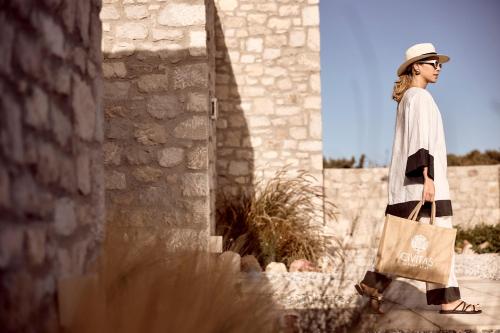 a woman walking down the street with a tote bag at Civitas Milos in Adamas