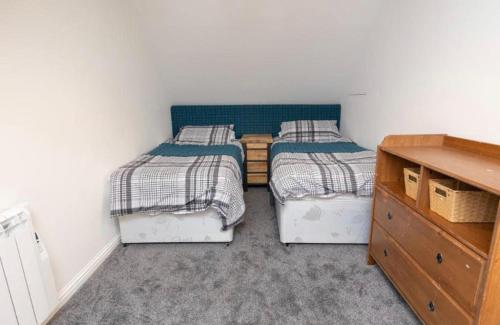 two twin beds in a small room with a dresser at Taigh John in Cluer