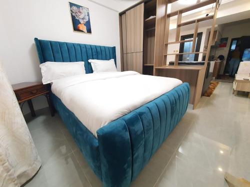 1 cama grande con cabecero azul en una habitación en Khomes cosy studio en Nairobi