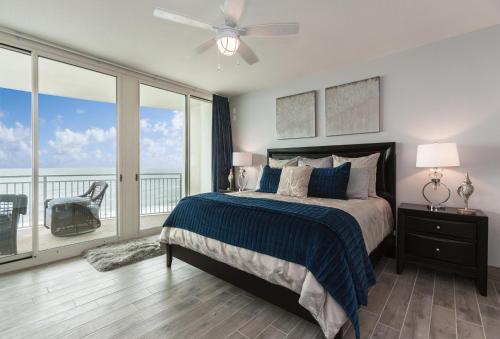 a bedroom with a bed with a ceiling fan and a balcony at Aqua 801 in Panama City Beach