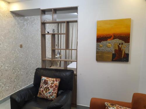 a living room with a leather chair and a painting at Khomes cosy studio in Nairobi