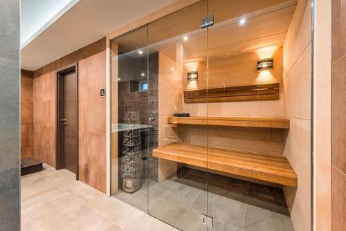 Elle comprend une douche à l'italienne avec des étagères en bois et une porte en verre. dans l'établissement Logement-sauna-spa-Strasbourg-Colmar-Europa Park, à Benfeld