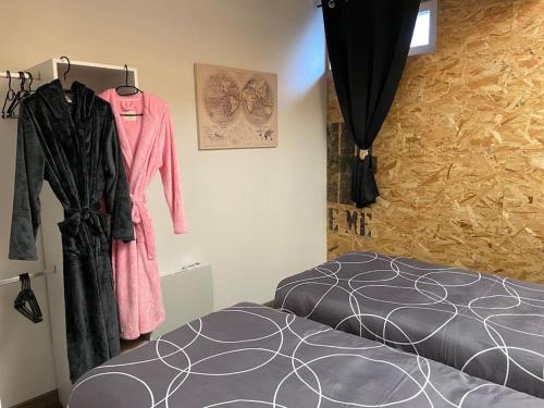 - une chambre avec un lit et des vêtements accrochés au mur dans l'établissement Logement-sauna-spa-Strasbourg-Colmar-Europa Park, à Benfeld