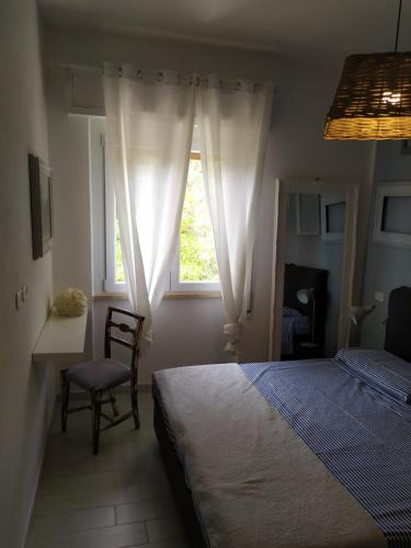 1 dormitorio con cama, ventana y silla en Bilocale a 40 mt. dalla spiaggia circondato dalla pineta, en Marina di Grosseto