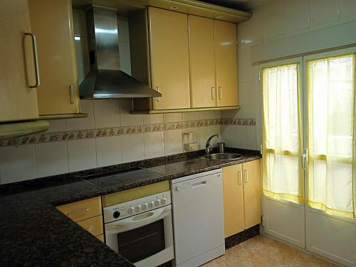 a kitchen with yellow cabinets and a sink and a stove at Mirador de las cigüeñas in Zamora