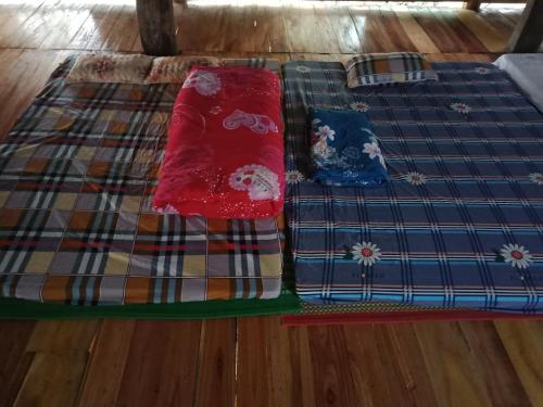 ein Bett mit zwei Kissen auf einem Holzboden in der Unterkunft Pù Luông Jungle Homestay in Pu Luong