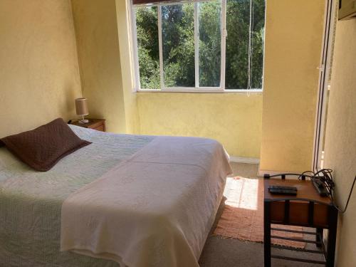 1 dormitorio con cama y ventana grande en APARTAMENTO PELICANOS VISTA JARDIN OLIVOS, en Puchuncaví