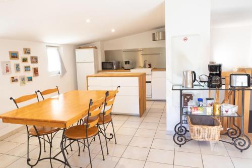 a kitchen and dining room with a wooden table and chairs at Appartement spacieux Rochereau in L'Isle-sur-la-Sorgue