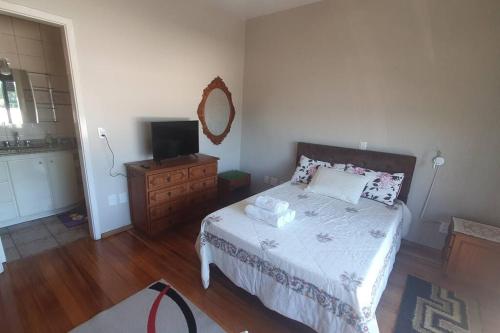 1 dormitorio con 1 cama con tocador y TV en Casa aconchegante e tranquila, em Veranópolis/RS., en Veranópolis