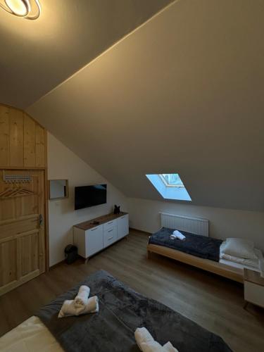 Schlafzimmer mit einem Bett, einem TV und einem Fenster in der Unterkunft Stara Piekarnia in Tylicz