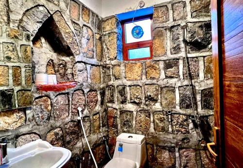 a bathroom with a stone wall with a toilet and a sink at Guest house baldsayt in Bilād Sayt