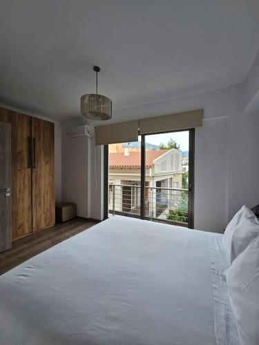 1 dormitorio con cama blanca y ventana grande en Cozy & Minimal Apartment Near Airport Peania, en Paianía