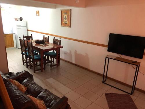 sala de estar con mesa y TV en Deptos PEHUEN -San Martín de los Andes- Centro - en San Martín de los Andes