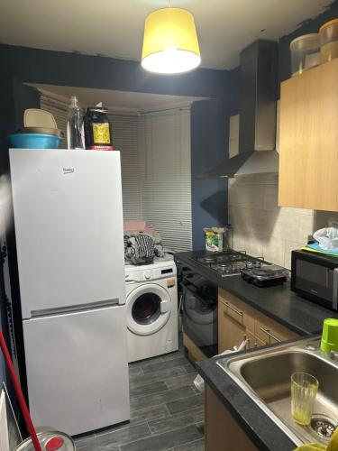 a kitchen with a white refrigerator and a washing machine at Forcare in Romford