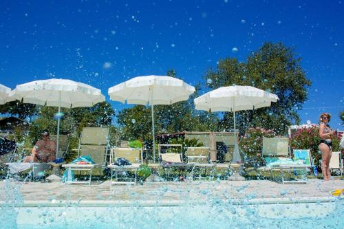 a group of people sitting under umbrellas at a pool at Tenuta Tredici Ulivi in Senigallia
