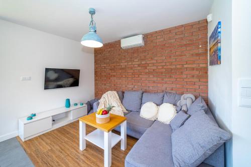 a living room with a blue couch and a brick wall at Forest House - Domy Mazur in Regiel