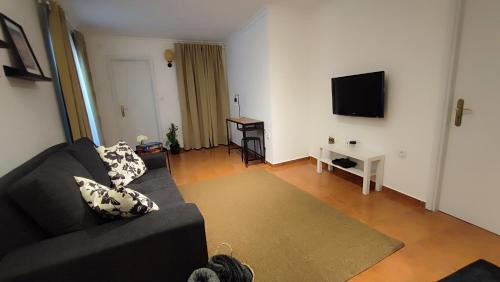 a living room with a black couch and a flat screen tv at The River House in Peso da Régua