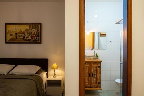 um quarto com uma cama e uma casa de banho com um chuveiro em Apartamento Le Quatre Centro Monte Verde em Monte Verde