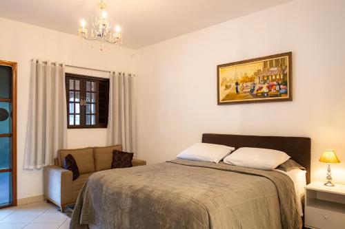 ein Schlafzimmer mit einem Bett und einem Stuhl in der Unterkunft Apartamento Le Quatre Centro Monte Verde in Monte Verde
