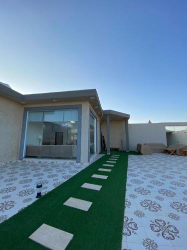 ein Haus mit grünem Rasen davor in der Unterkunft شاليهات ملك in Rafha