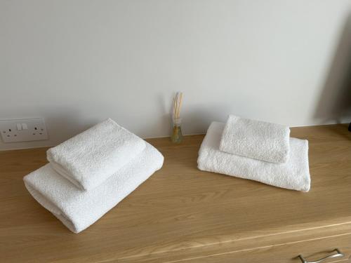 two white towels sitting on top of a wooden dresser at Delightful self-contained Annexe close to airport in Norwich