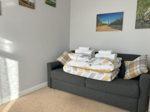 un sofá con una pila de mantas y almohadas en Delightful self-contained Annexe close to airport en Norwich